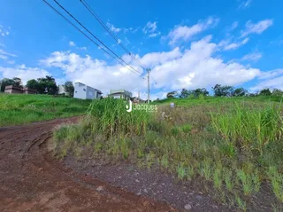 Uma estrada de terra leva a um campo de grama verde sob um céu azul.