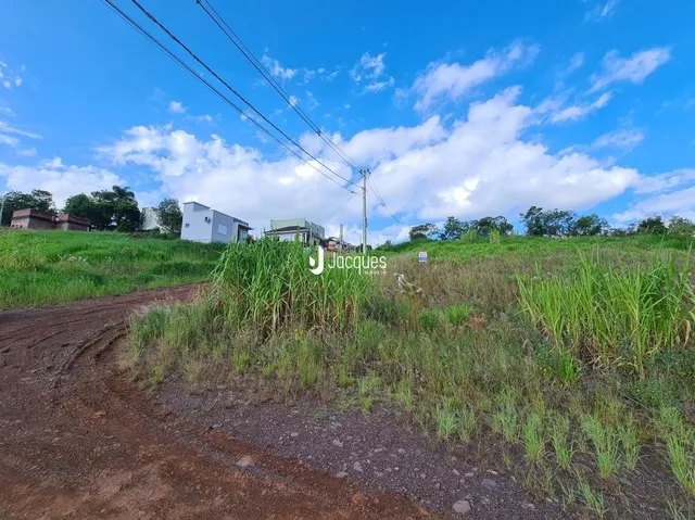 Uma estrada de terra leva a um campo de grama verde sob um céu azul.