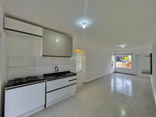 Interior de uma cozinha moderna com armários brancos e piso claro.