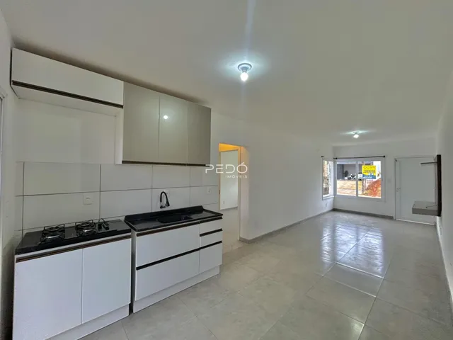 Interior de uma cozinha moderna com armários brancos e piso claro.