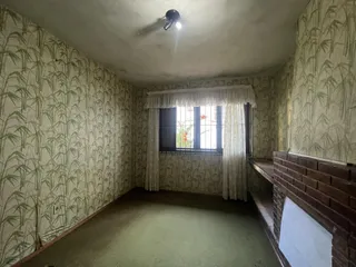 Sala de estar com paredes decoradas com papel de parede de bambu e uma janela.