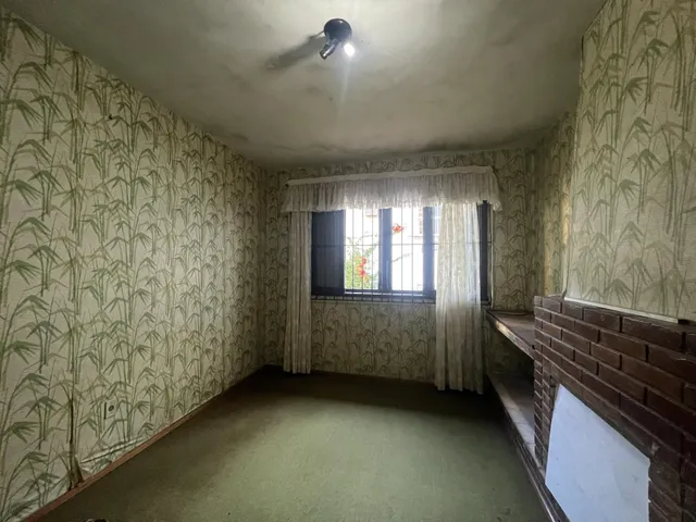 Sala de estar com paredes decoradas com papel de parede de bambu e uma janela.