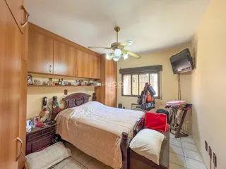 Quarto com cama de madeira e armários em um imóvel no Brasil.