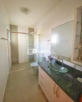 Foto de um banheiro com bancada escura e box de vidro.