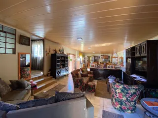 Interior de uma sala de estar ampla com piso de cerâmica e móveis de madeira escura.