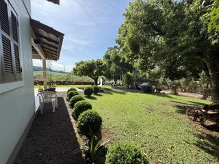 Vista da fachada de uma residência com jardim e árvores.