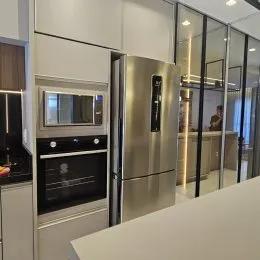 Foto de um interior de cozinha com armários brancos e eletrodomésticos de aço inoxidável.