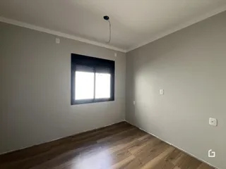 Ambiente interno de uma sala com piso de madeira e janela.