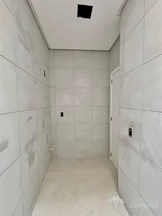 Um corredor interno com paredes brancas e piso claro.