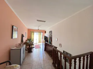 Hall de entrada com piso de cerâmica e corrimão de madeira.