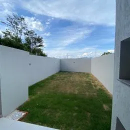 Vista de um jardim gramado cercado por muros brancos.