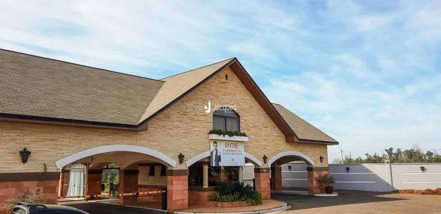 Fachada de uma residência com telhado inclinado e detalhes em tijolo aparente.