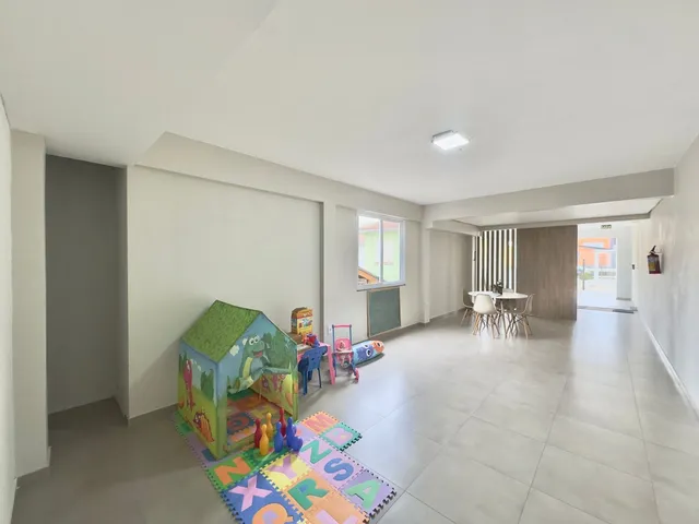 Ambiente interno amplo com área de lazer infantil e mesa de jantar.