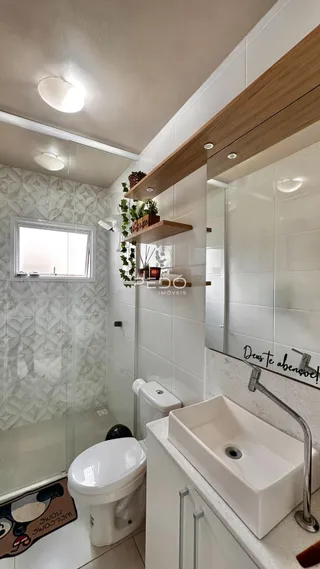 Banheiro moderno com revestimento branco e piso claro.