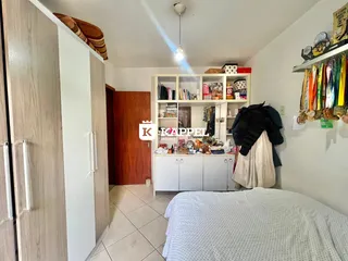 Quarto com cama, estante de livros e armário branco.