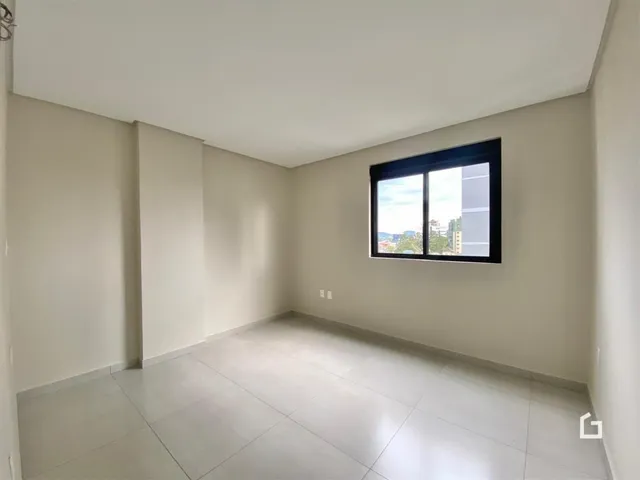 Ambiente interno de uma sala com piso de cerâmica e janela para a vista.