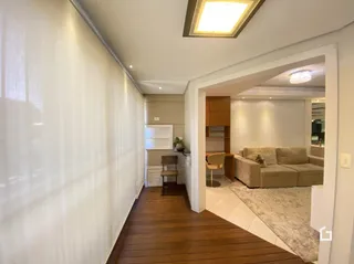 Corredor interno com piso de madeira e parede branca.