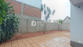 Vista externa da propriedade com parede de tijolos e pátio cerâmico.