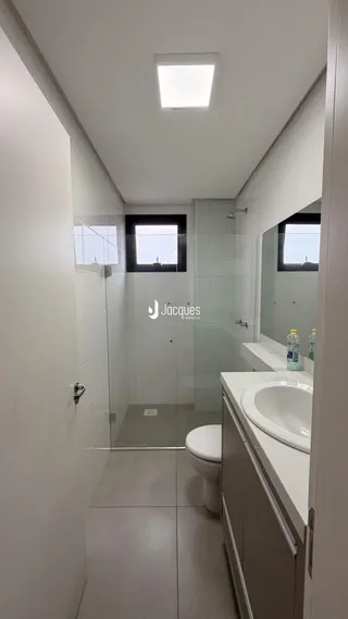 Banheiro moderno com box de vidro e revestimento cerâmico.