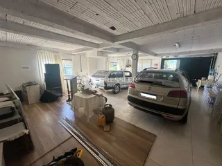 Interior de uma sala com piso de madeira e teto de vigas expostas.