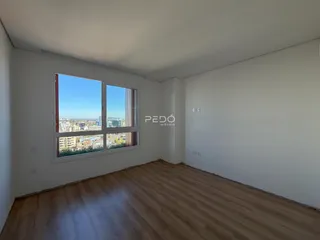 Sala de estar com piso de madeira e grande janela de vista para a cidade.