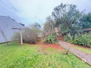 Vista externa da propriedade com gramado e muro de tijolos.