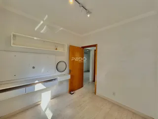 Interior de uma sala com paredes brancas e piso de madeira clara.
