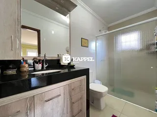 Foto de um banheiro com bancada escura e box de vidro.