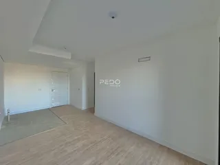 Hall de entrada com piso de madeira clara e paredes brancas.