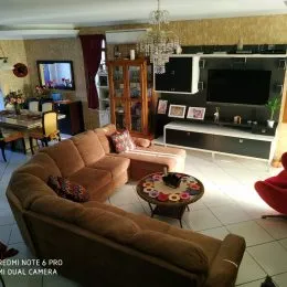 Foto de uma sala de estar com sofá marrom e televisão montada na parede.