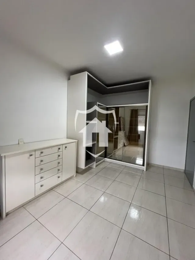Interior de um ambiente com piso de cerâmica e armários brancos.