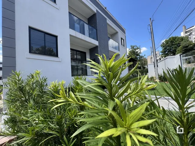 Fachada de um prédio residencial em Lajeado, Brasil com vegetação em primeiro plano.
