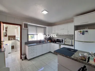 Cozinha moderna com armários brancos e bancadas escuras.