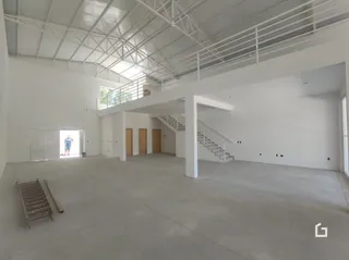 Foto de um espaço interno com teto alto e estrutura de vigas exposta.