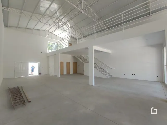 Foto de um espaço interno com teto alto e estrutura de vigas exposta.