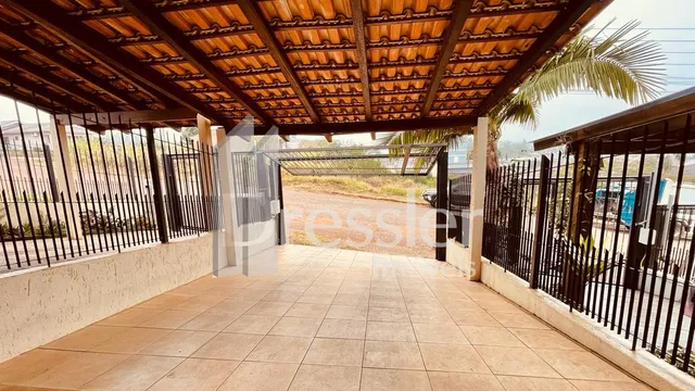 Vista de um pátio coberto com piso de cerâmica e grade de ferro na propriedade.