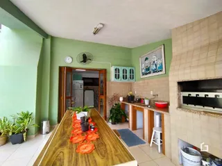 Vista da cozinha com piso de madeira e parede verde na propriedade.