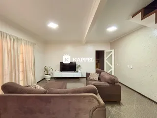 Sala de estar com sofás e televisão em um ambiente claro.