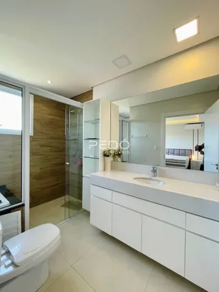Banheiro moderno com box de vidro e revestimento claro.