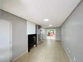 Hall de uma residência com piso claro e lareira na parede.