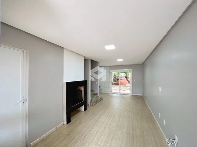 Hall de uma residência com piso claro e lareira na parede.