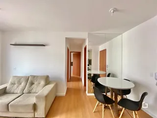 Sala de estar com sofá e mesa de jantar em um apartamento.