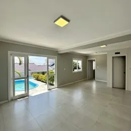 Ambiente interno com piso claro e vista para uma área externa com piscina.