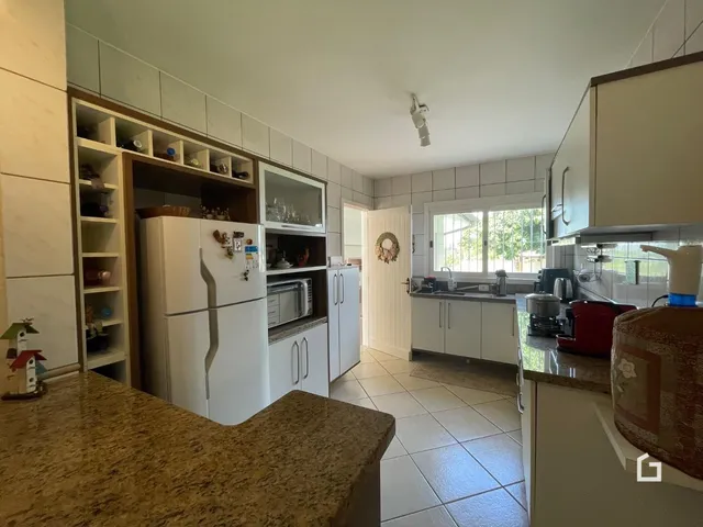 Cozinha com armários brancos e piso de cerâmica em imóvel no Brasil.