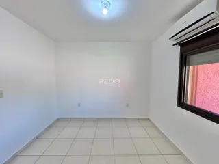 Ambiente interno de uma sala com piso de cerâmica clara e paredes brancas.