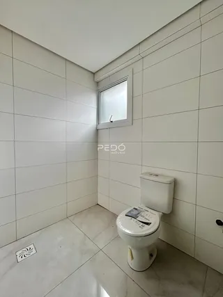 Foto de um banheiro com revestimento cerâmico branco.