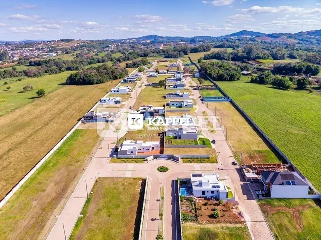 Vista aérea de uma propriedade rural com campos verdes e estruturas dispersas.
