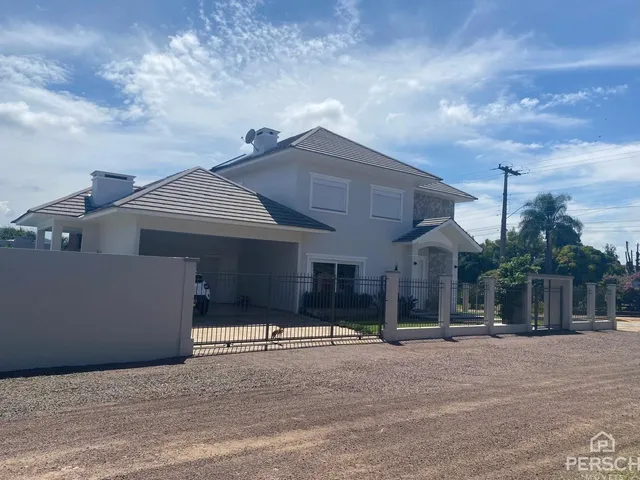 Fachada de uma casa branca em Lajeado, Brasil, com muro e portão de segurança.