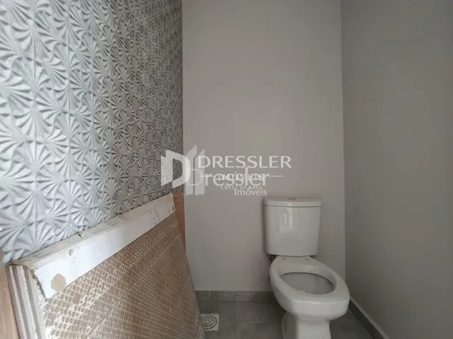 Foto de um ambiente interno mostrando uma parede texturizada e um vaso sanitário branco.