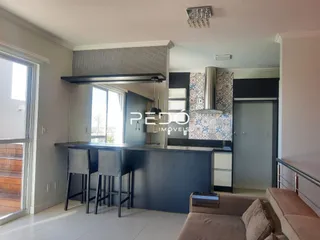 Ambiente interno de uma sala de estar com cozinha integrada.
